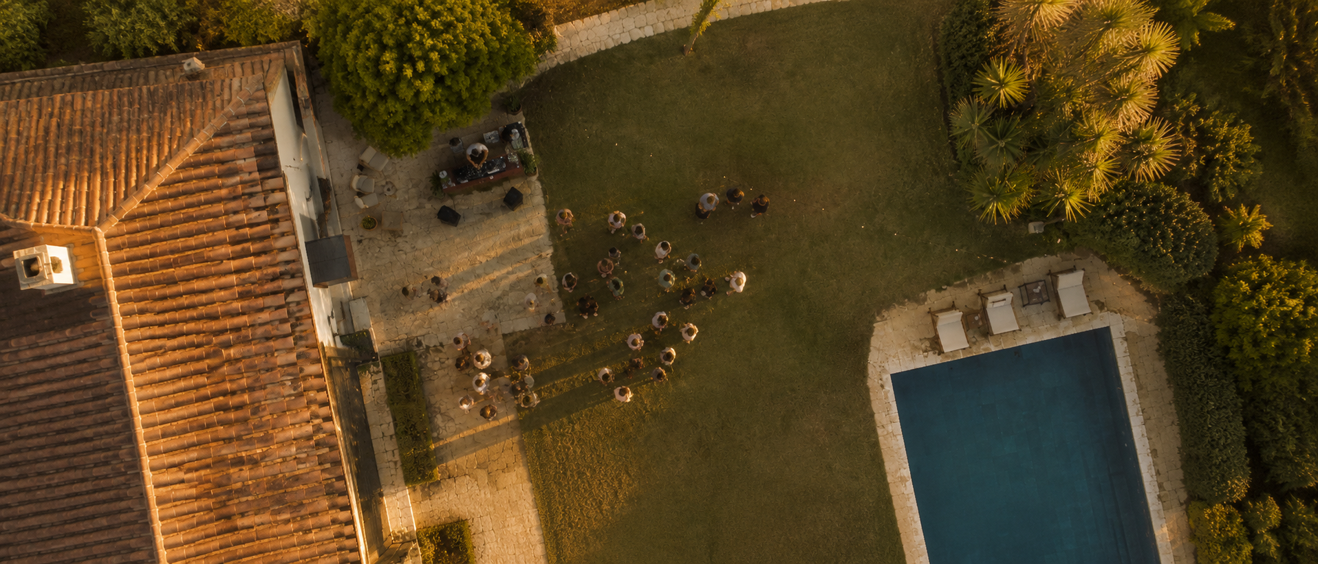 Aerial view of a garden party by a pool at sunset
